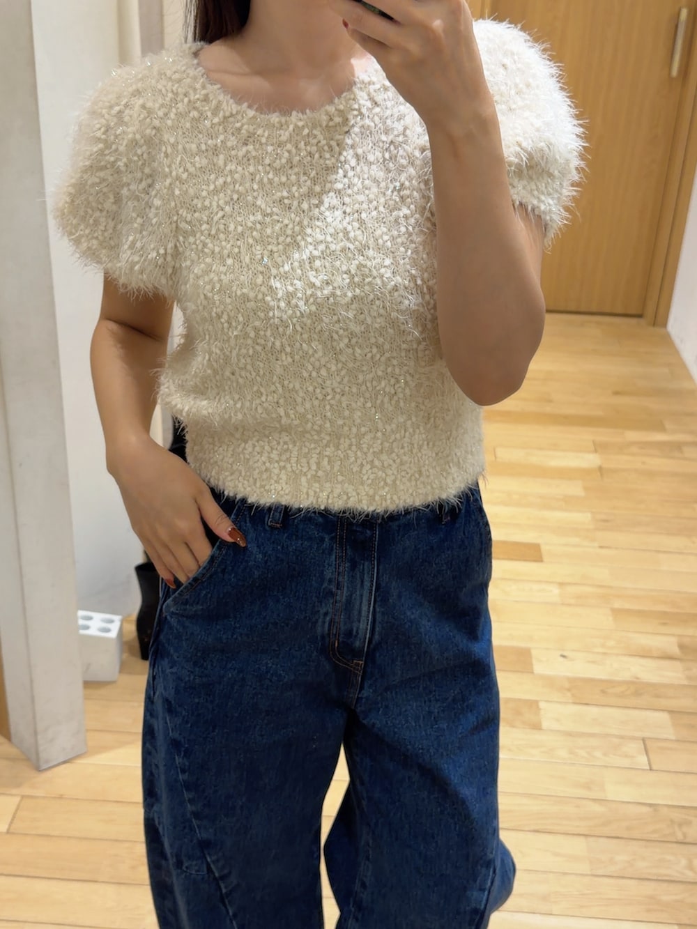ブルー系のデニムパンツ、レッド系のハンドバッグ、ブラック系のブーツを着用したレディースの秋コーディネートの8枚目の写真