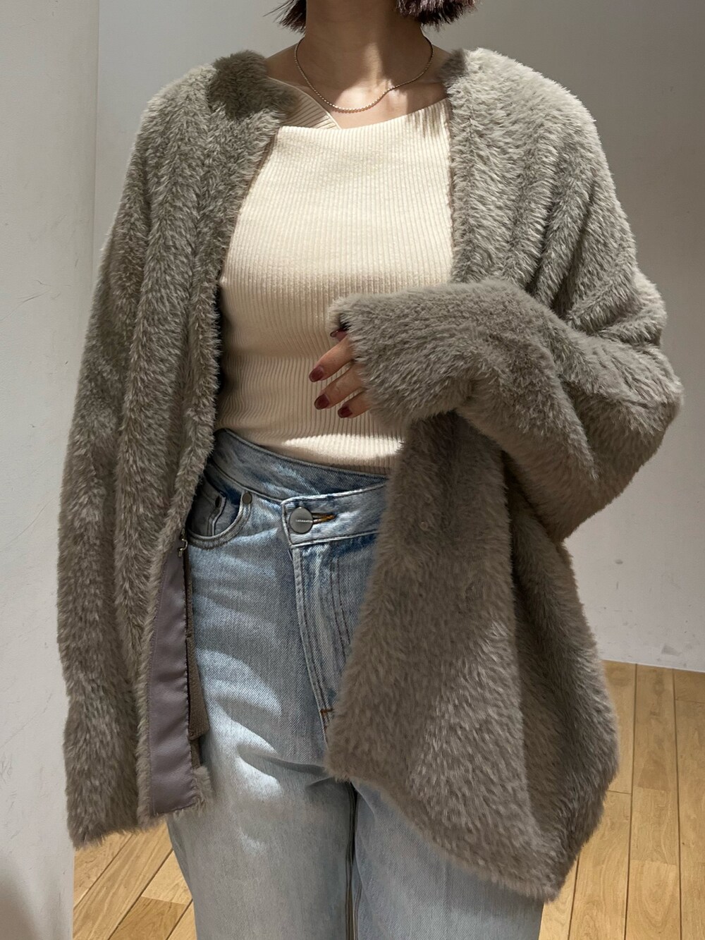 ブルー系のデニムパンツ、ホワイト系のニット/セーター、ブラウン系のカーディガン/ボレロを着用したレディースの秋コーディネートの4枚目の写真