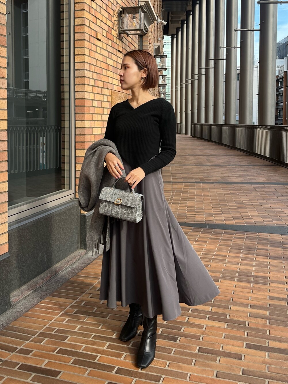ホワイト系のノーカラーコート、ブラック系のワンピース、グレー系のショルダーバッグを着用したレディースの冬コーディネートの5枚目の写真