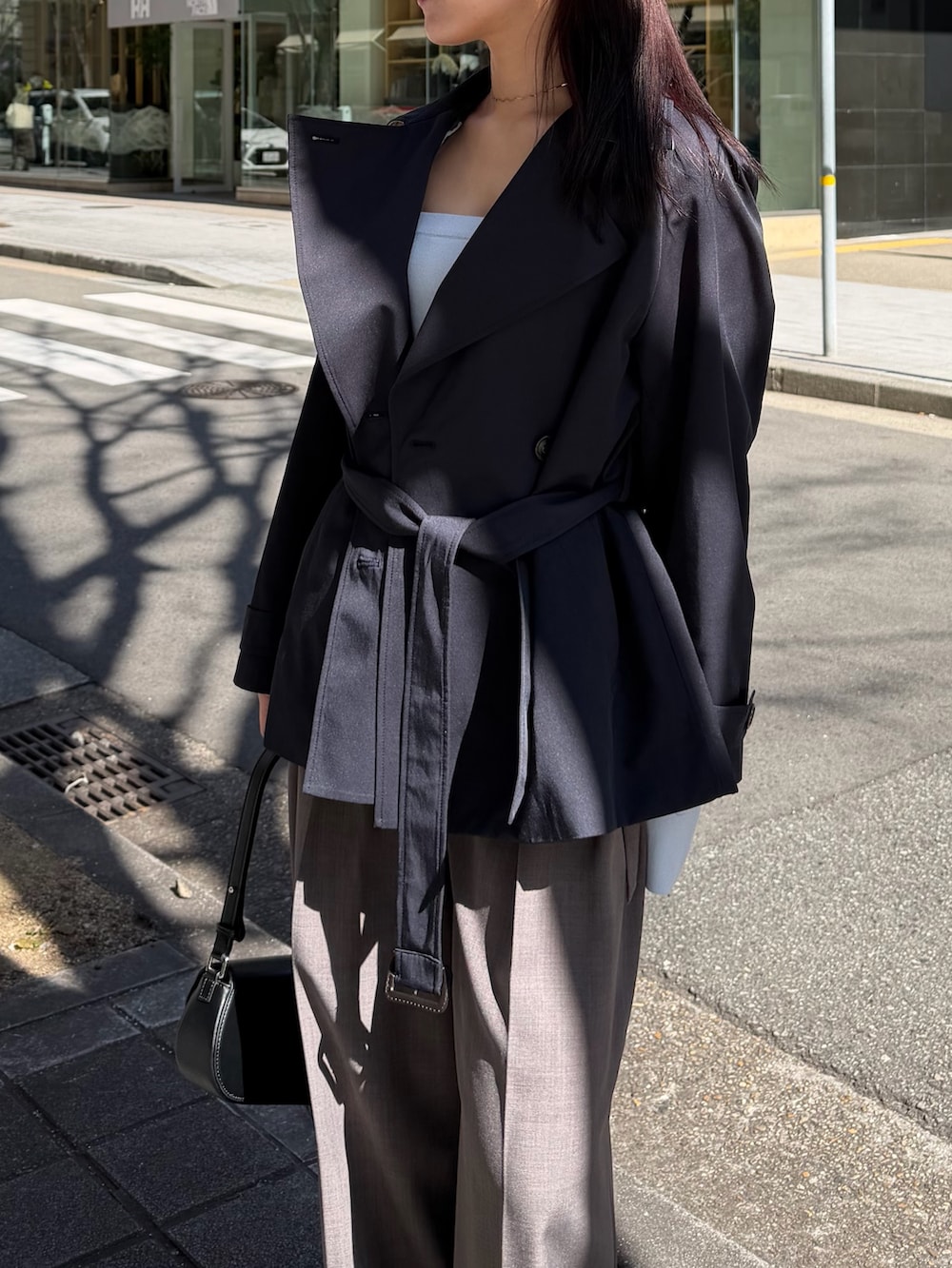 ブルー系のトレンチコート、グレー系のその他パンツ、ブラック系のハンドバッグを着用したレディースの冬コーディネートの4枚目の写真