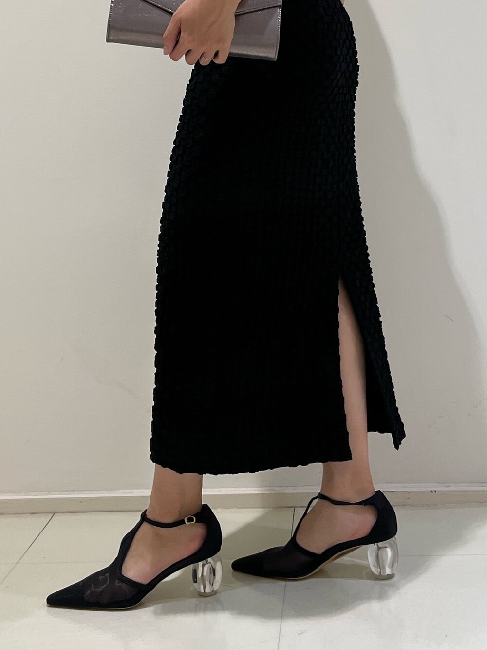 シルバー系のハンドバッグ、ブラック系のパンプス、ブラック系のドレスを着用したレディースの冬コーディネートの7枚目の写真