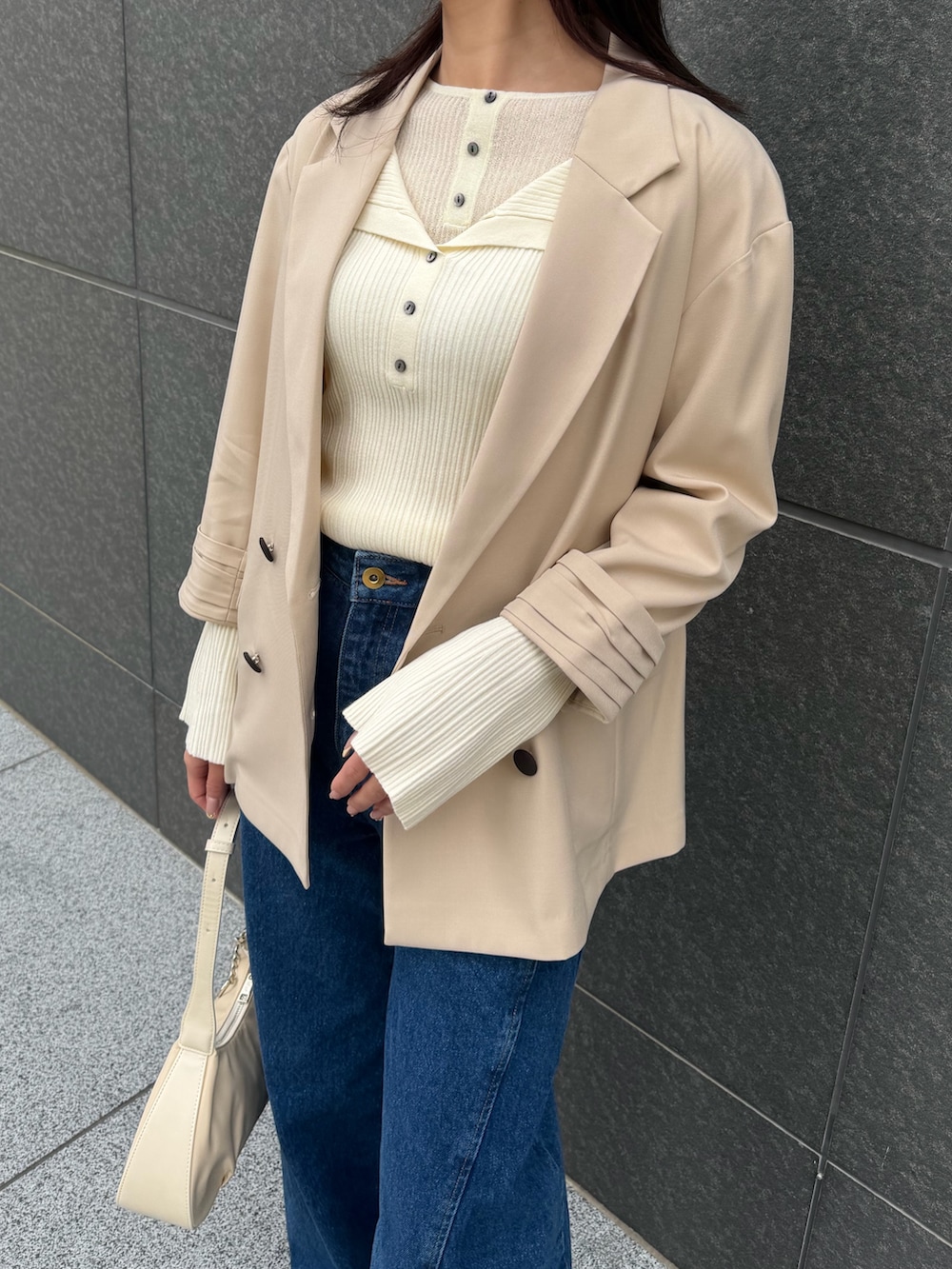 ベージュ系のテーラードジャケット、ホワイト系のニット/セーター、ブルー系のデニムパンツを着用したレディースの春コーディネートの5枚目の写真