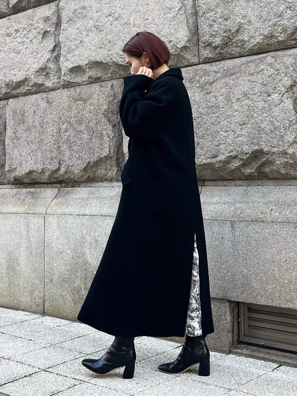 ホワイト系のワンピース、ブラック系のチェスターコート、ブラック系のハンドバッグを着用したレディースの冬コーディネートの4枚目の写真