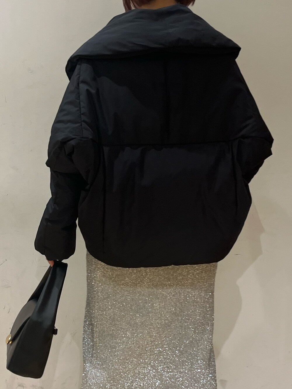 ブラック系のブーツ、ブラック系のハンドバッグ、シルバー系のスカートを着用したレディースの冬コーディネートの7枚目の写真