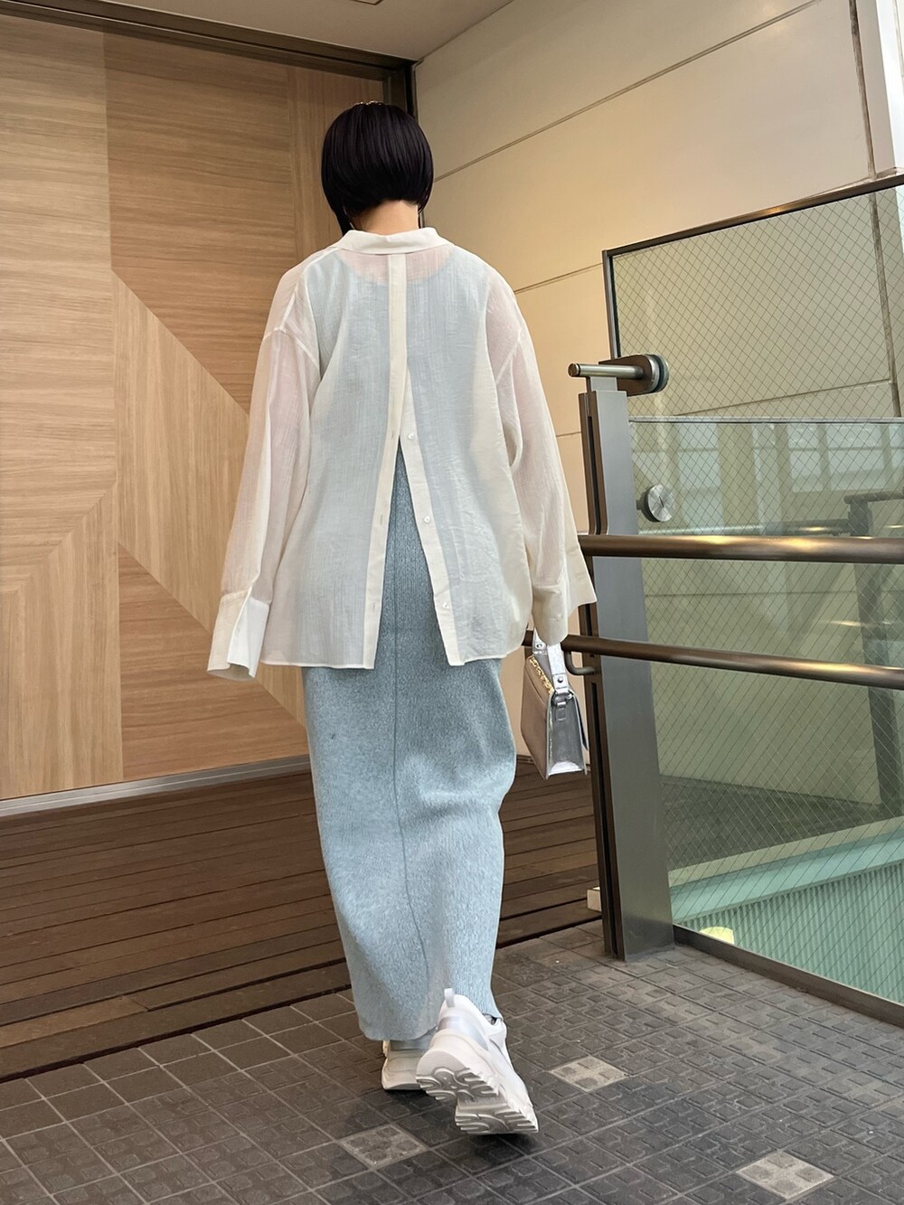 シルバー系のショルダーバッグ、ホワイト系のスニーカー、ブルー系のワンピースを着用したレディースの春コーディネートの3枚目の写真