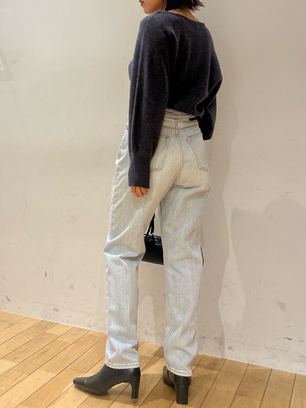 グレー系のニット/セーター、ブルー系のデニムパンツ、ブラック系のショルダーバッグを着用したレディースの秋コーディネートの3枚目の写真