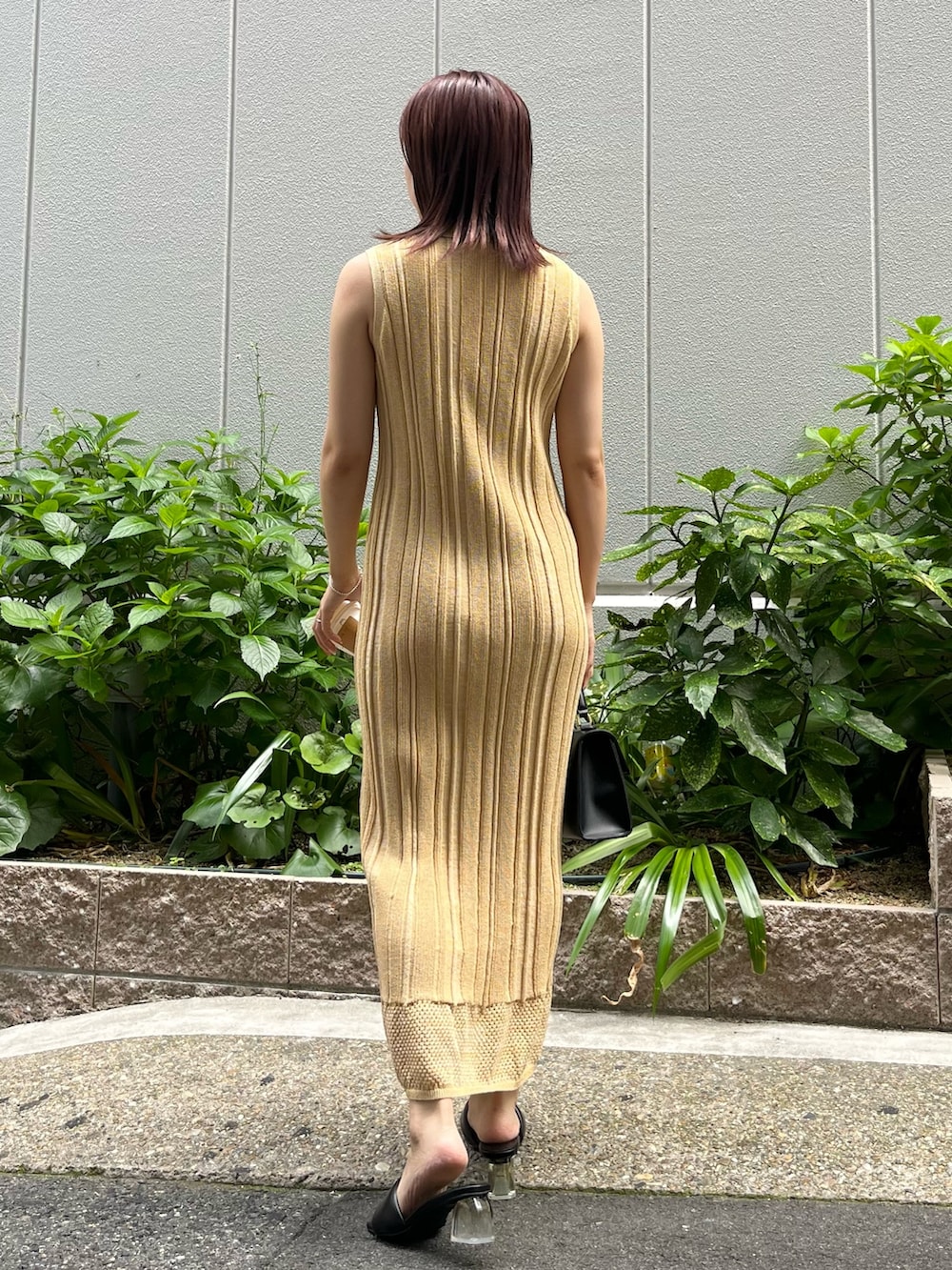 イエロー系のワンピース、ブラック系のハンドバッグ、ブラック系のサンダルを着用したレディースの夏コーディネートの3枚目の写真