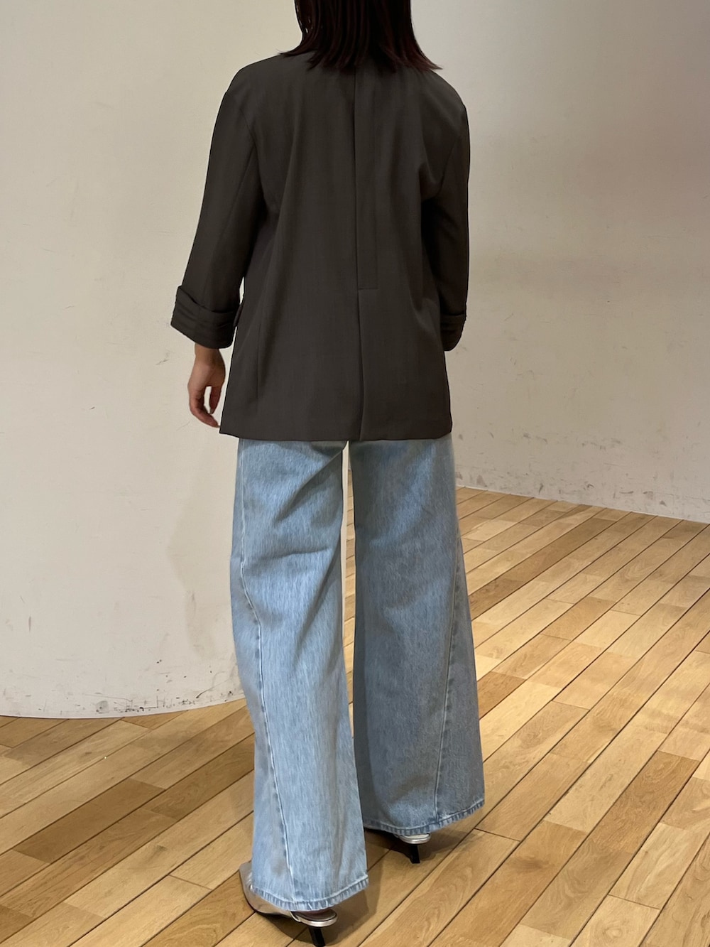 グレー系のテーラードジャケット、ブルー系のデニムパンツ、シルバー系のサンダルを着用したレディースの春コーディネートの3枚目の写真