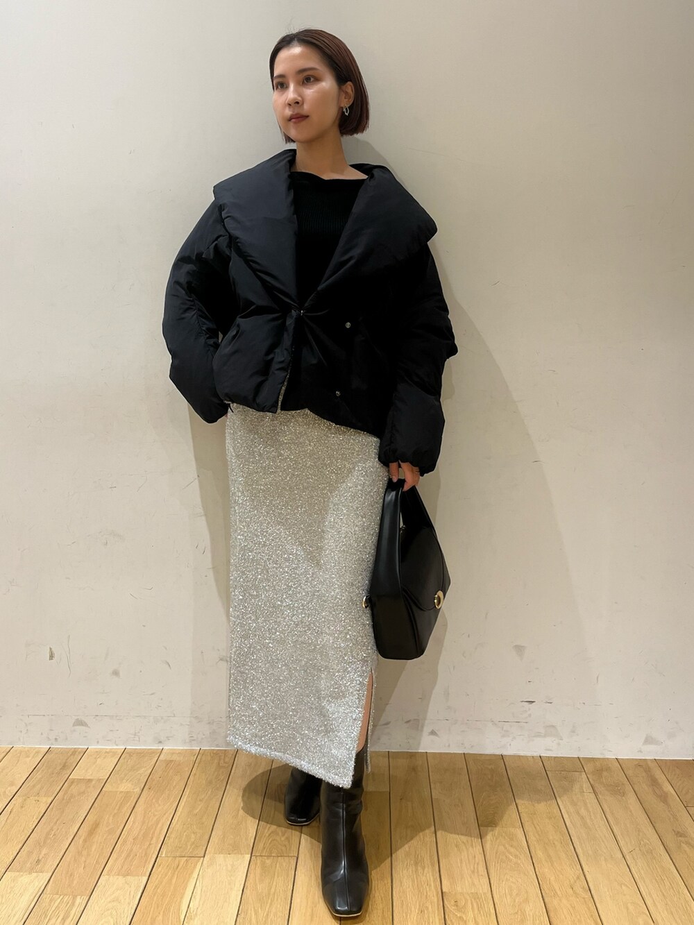 ブラック系のブーツ、ブラック系のハンドバッグ、シルバー系のスカートを着用したレディースの冬コーディネートの2枚目の写真