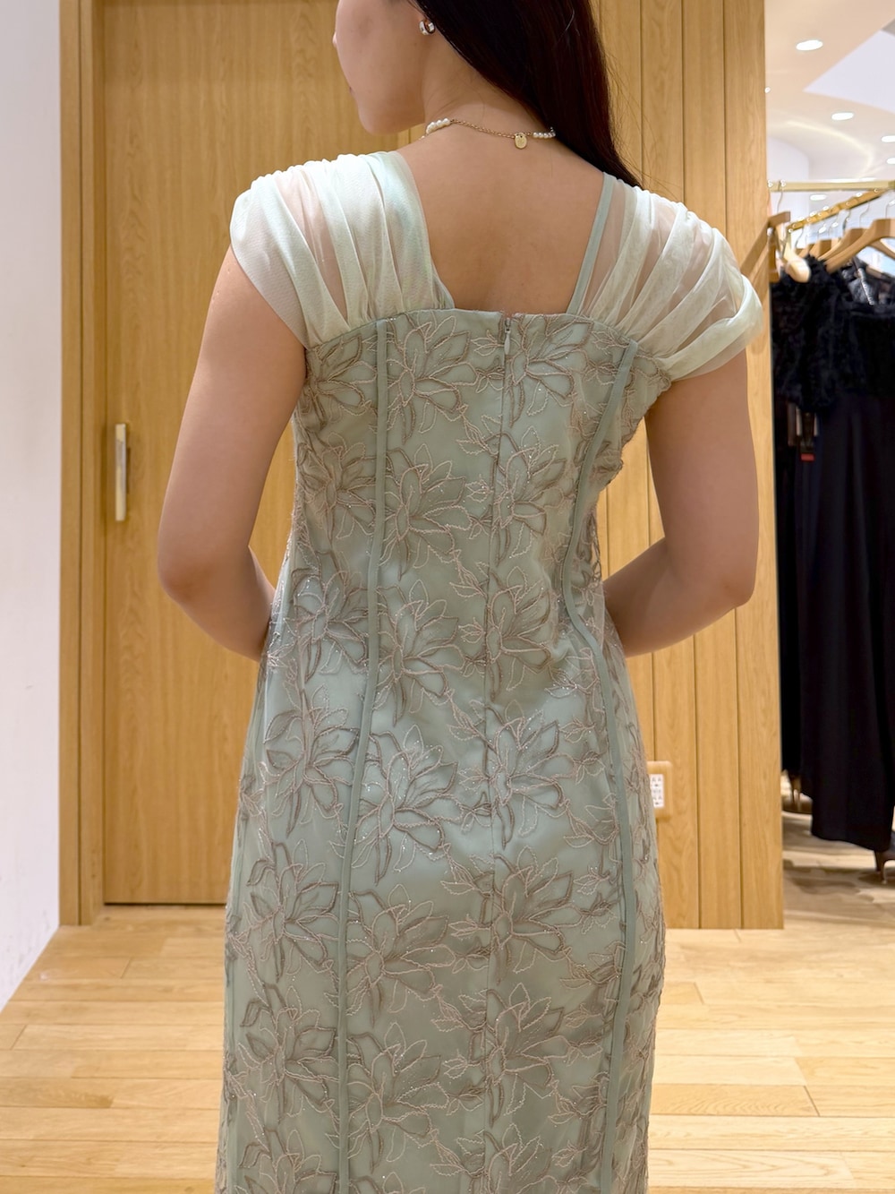 ブラック系のパンプス、ブラック系のクラッチバッグ、グリーン系のワンピースを着用したレディースの夏コーディネートの6枚目の写真
