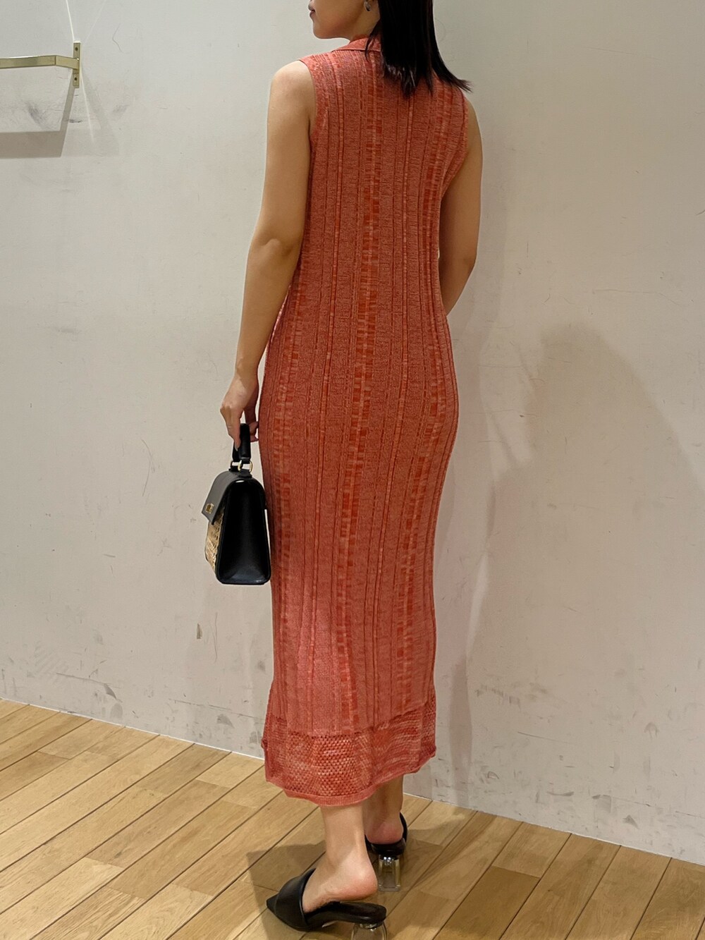 ブラック系のハンドバッグ、ブラック系のサンダル、オレンジ系のワンピースを着用したレディースの夏コーディネートの3枚目の写真