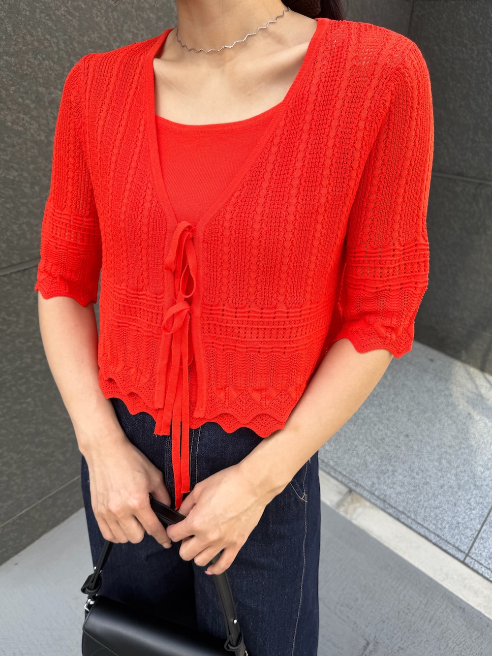 ブルー系のデニムパンツ、オレンジ系のアンサンブルを着用したレディースの春コーディネートの6枚目の写真