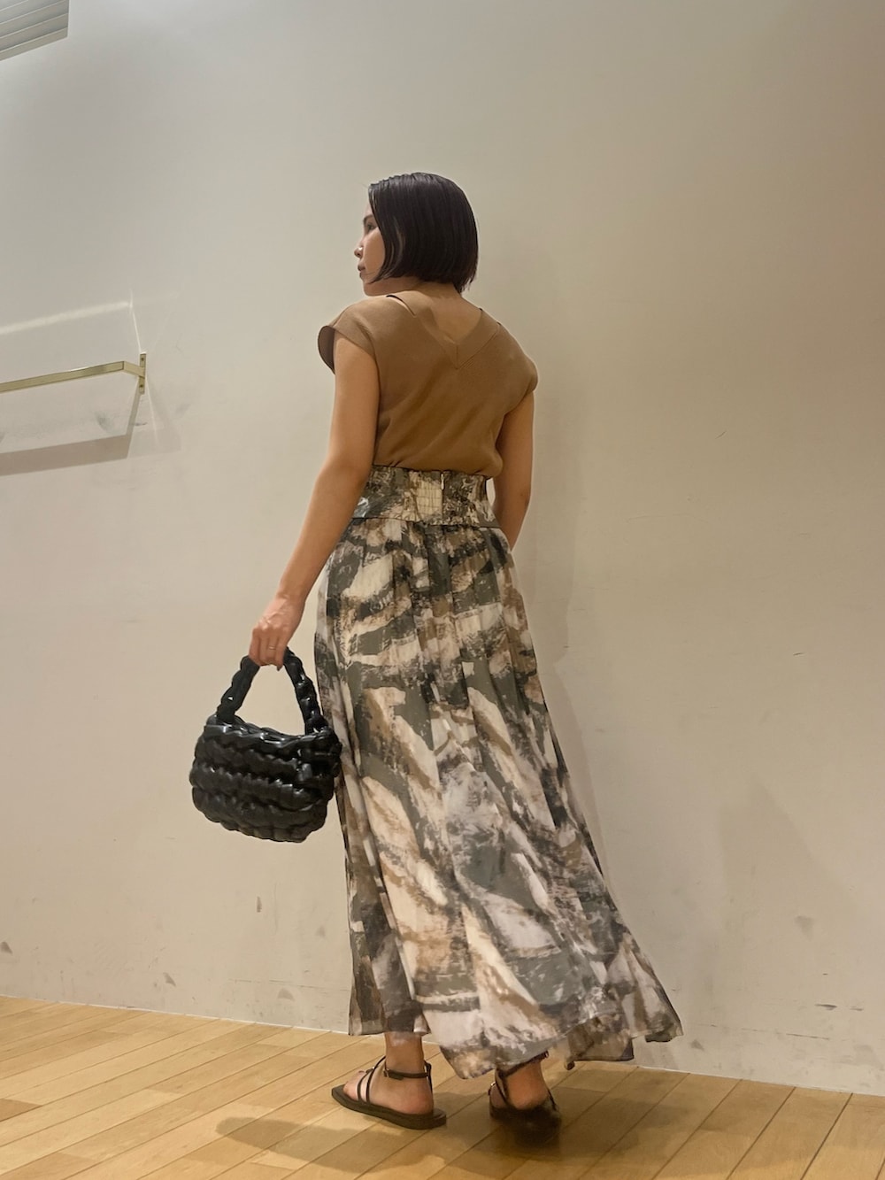 グレー系のスカート、ブラウン系のニット/セーター、ブラック系のサンダルを着用したレディースの夏コーディネートの4枚目の写真