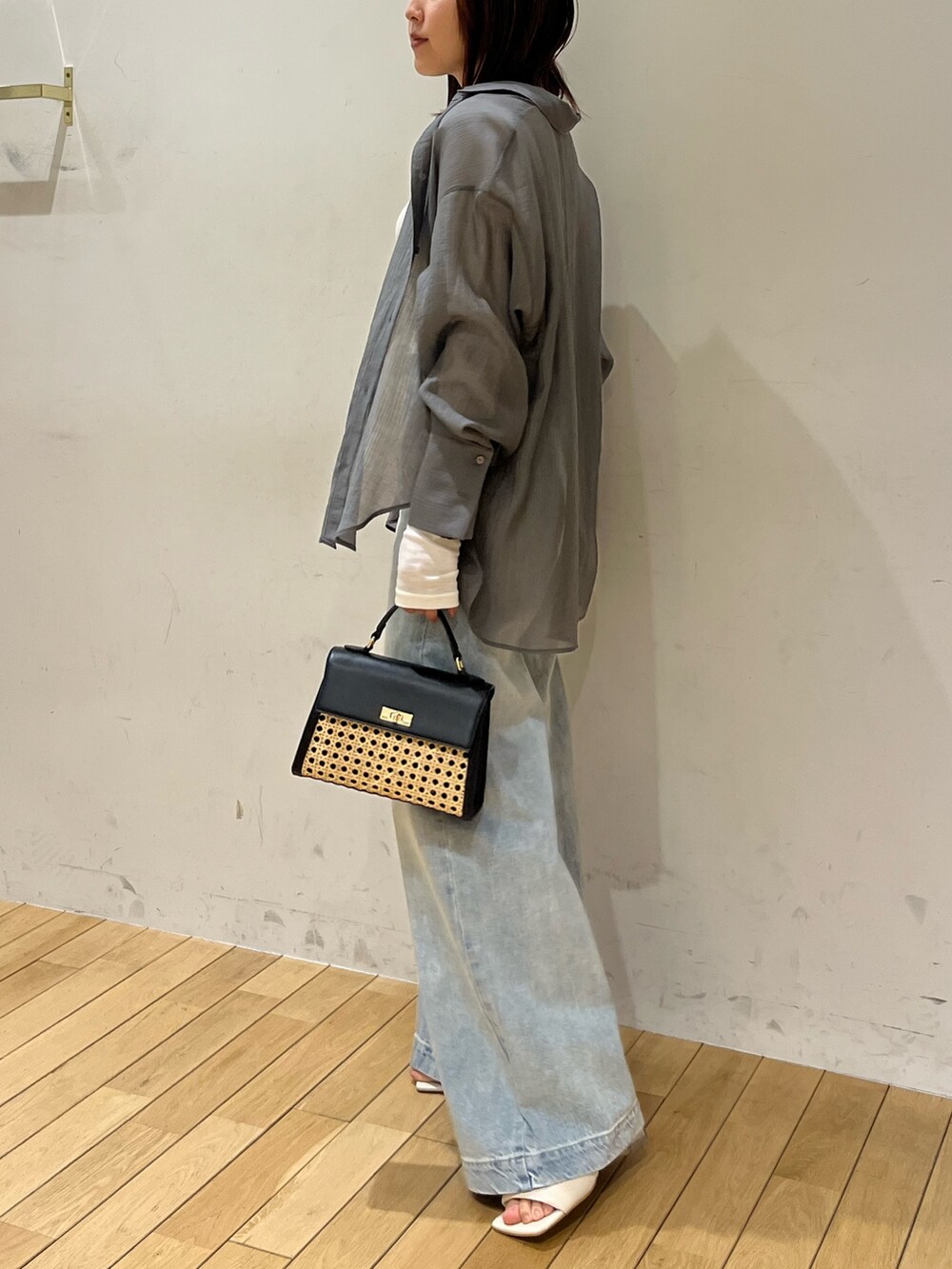 ホワイト系のサンダル、ブラック系のハンドバッグ、ブルー系のデニムパンツを着用したレディースの春コーディネートの2枚目の写真