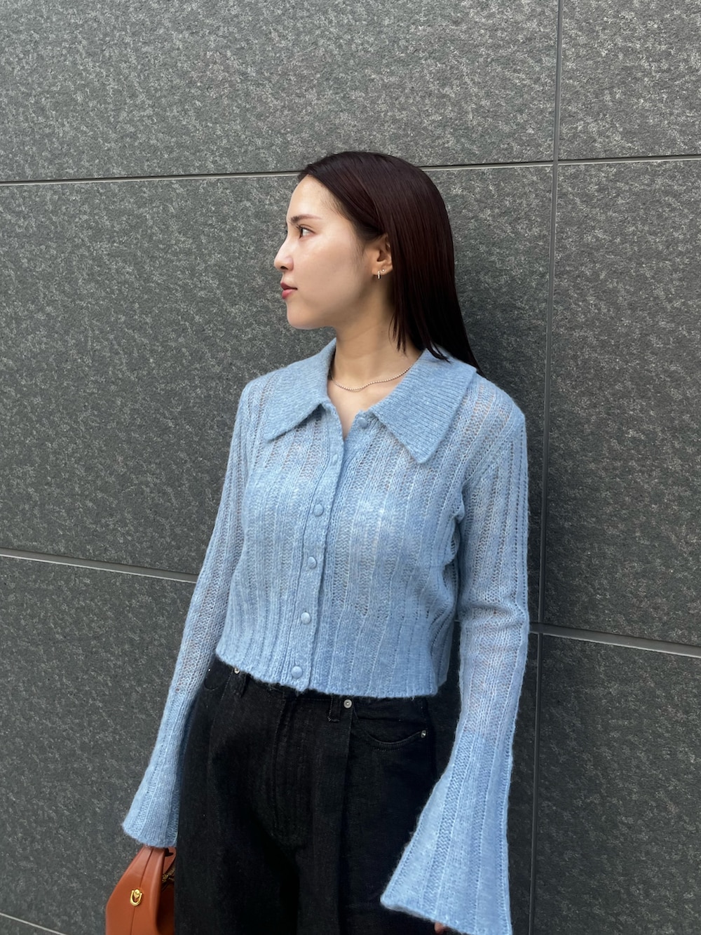 ブルー系のニット/セーター、ブラック系のデニムパンツ、ブラウン系のハンドバッグを着用したレディースの秋コーディネートの5枚目の写真