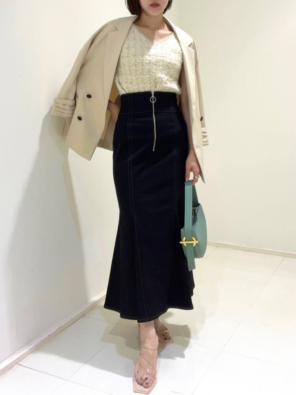 ベージュ系のテーラードジャケット、ホワイト系のニット/セーター、ブラック系のスカートを着用したレディースの春コーディネートの3枚目の写真