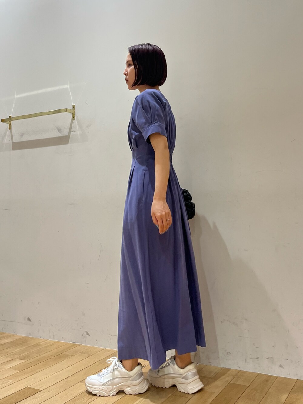 ブルー系のワンピース、ブラック系のハンドバッグ、ホワイト系のスニーカーを着用したレディースの夏コーディネートの2枚目の写真