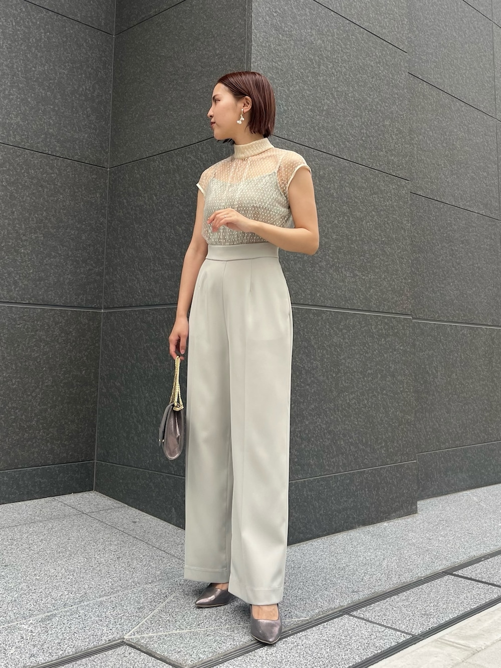 シルバー系のハンドバッグ、シルバー系のパンプス、グリーン系のパンツドレスを着用したレディースの春コーディネートの2枚目の写真