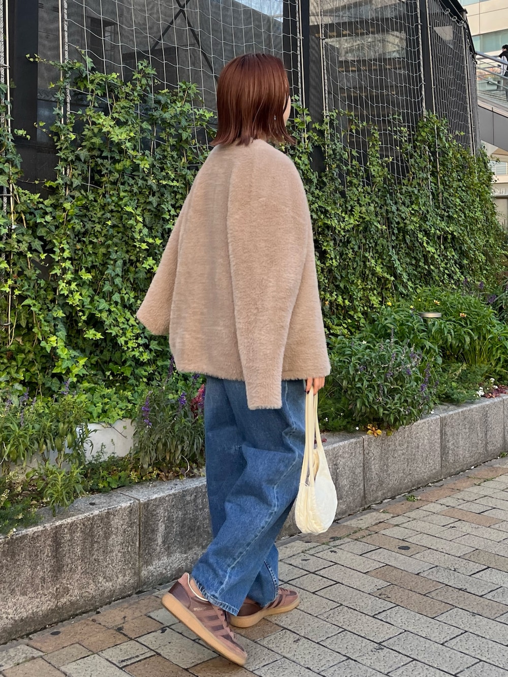 ブルー系のニット/セーター、ブルー系のデニムパンツ、ブラウン系のカーディガン/ボレロを着用したレディースの冬コーディネートの2枚目の写真