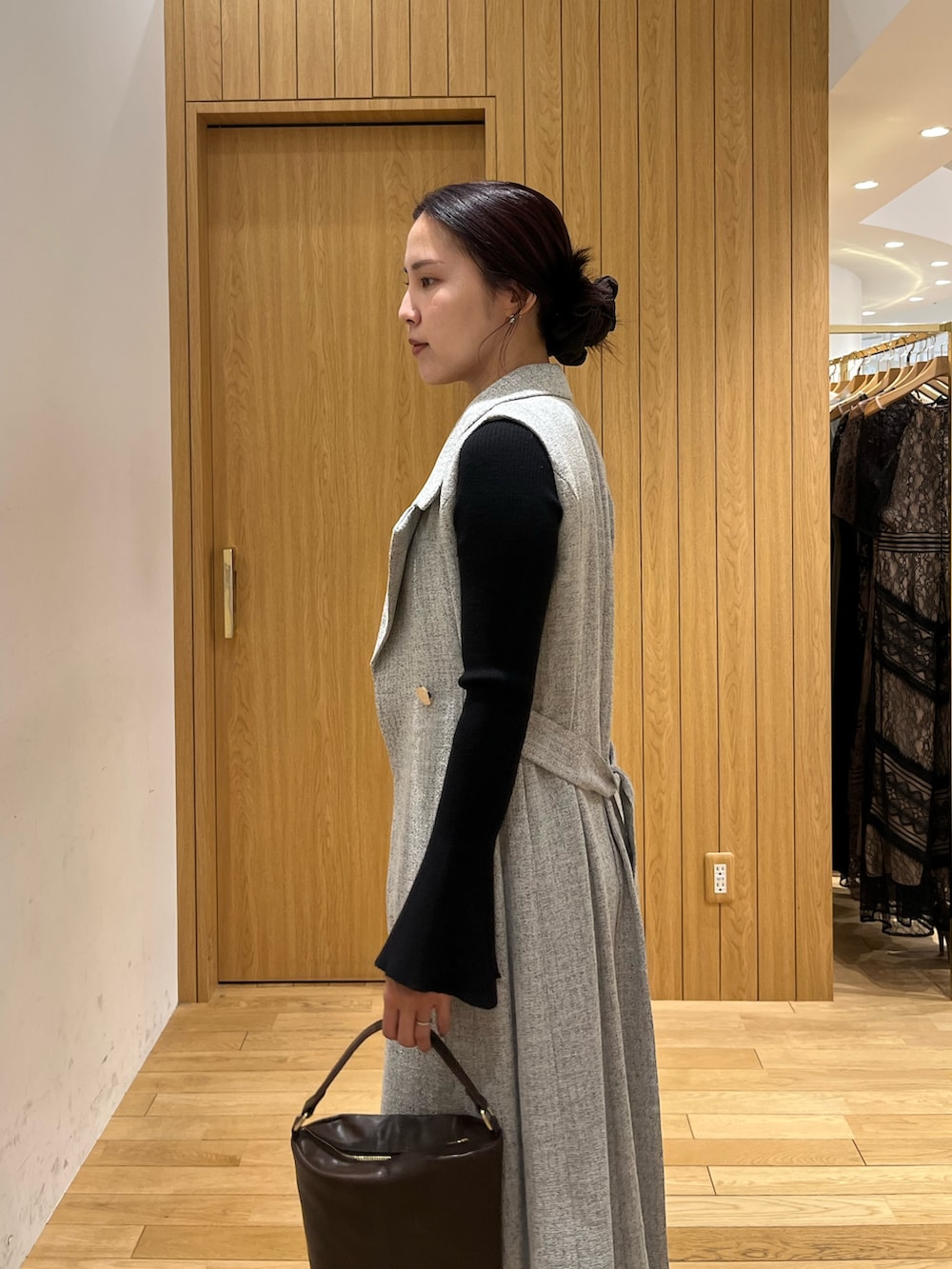 ブラウン系のハンドバッグ、ブラック系のデニムパンツ、グレー系のワンピースを着用したレディースの秋コーディネートの5枚目の写真