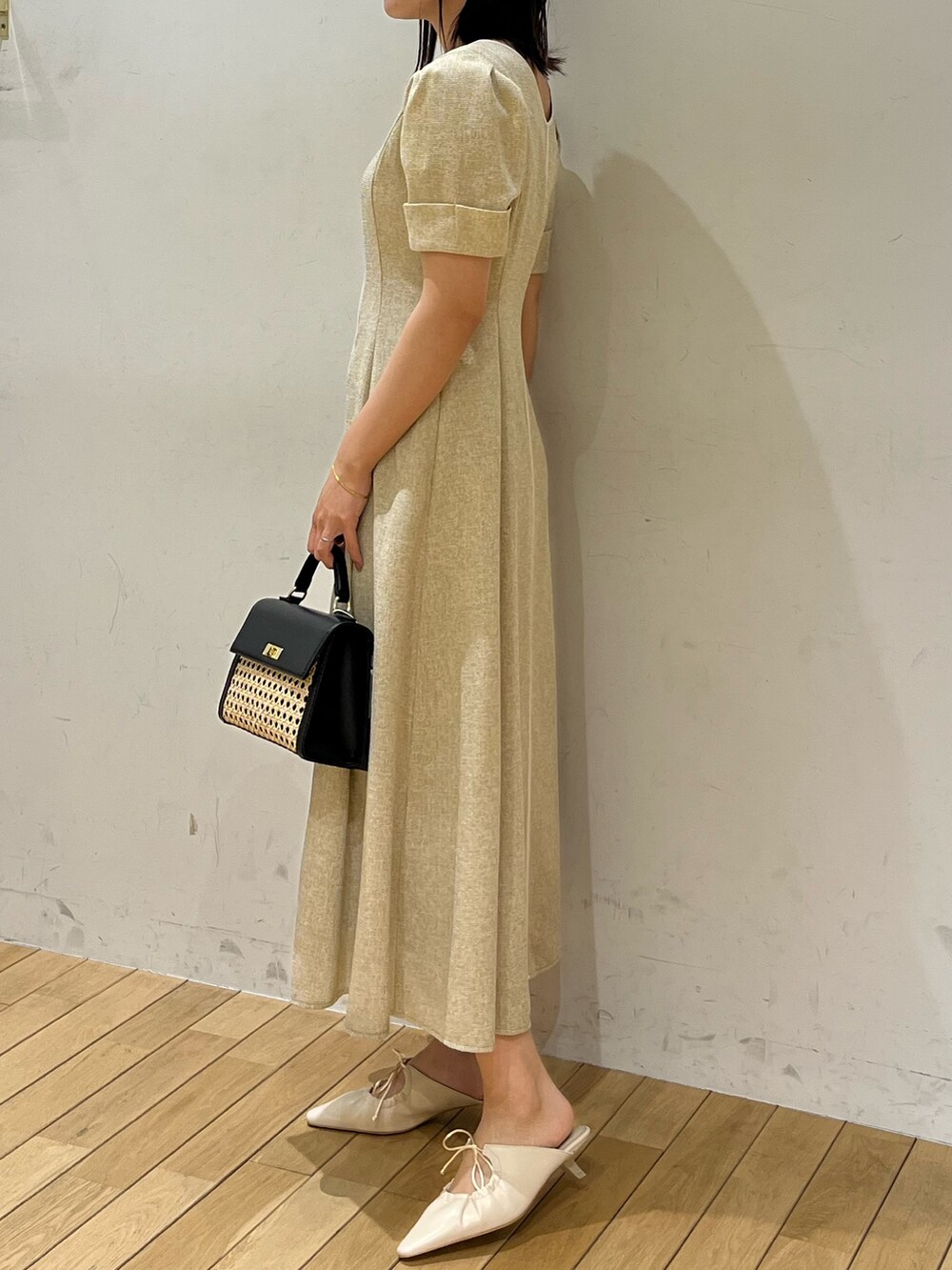 ベージュ系のワンピース、ホワイト系のサンダル、ブラック系のハンドバッグを着用したレディースの春コーディネートの2枚目の写真