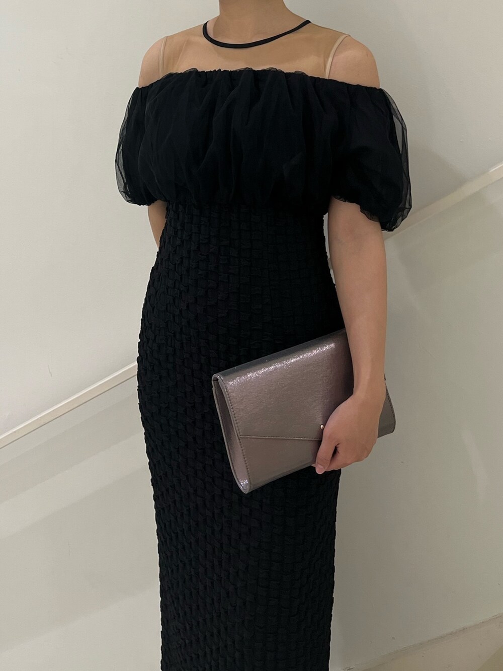 シルバー系のハンドバッグ、ブラック系のパンプス、ブラック系のドレスを着用したレディースの冬コーディネートの4枚目の写真