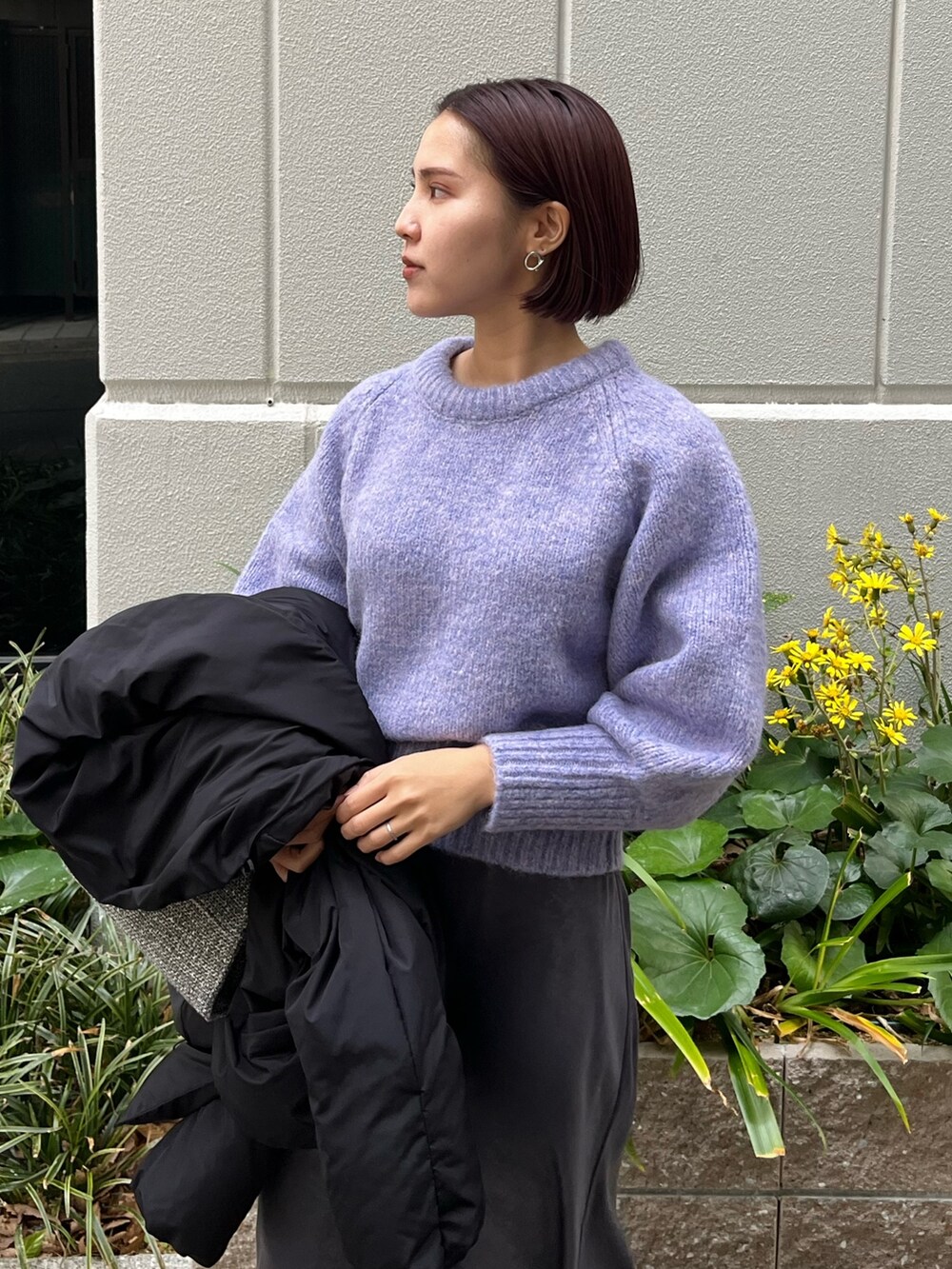 グレー系のスカート、パープル系のニット/セーター、ブラック系のダウンジャケット/コートを着用したレディースの冬コーディネートの5枚目の写真