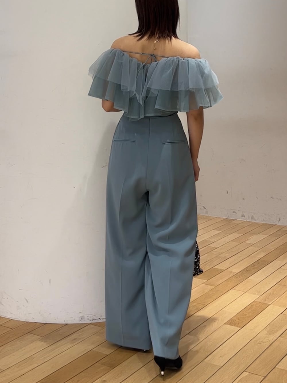 シルバー系のショルダーバッグ、ブラック系のパンプス、ブルー系のパンツドレスを着用したレディースの春コーディネートの3枚目の写真