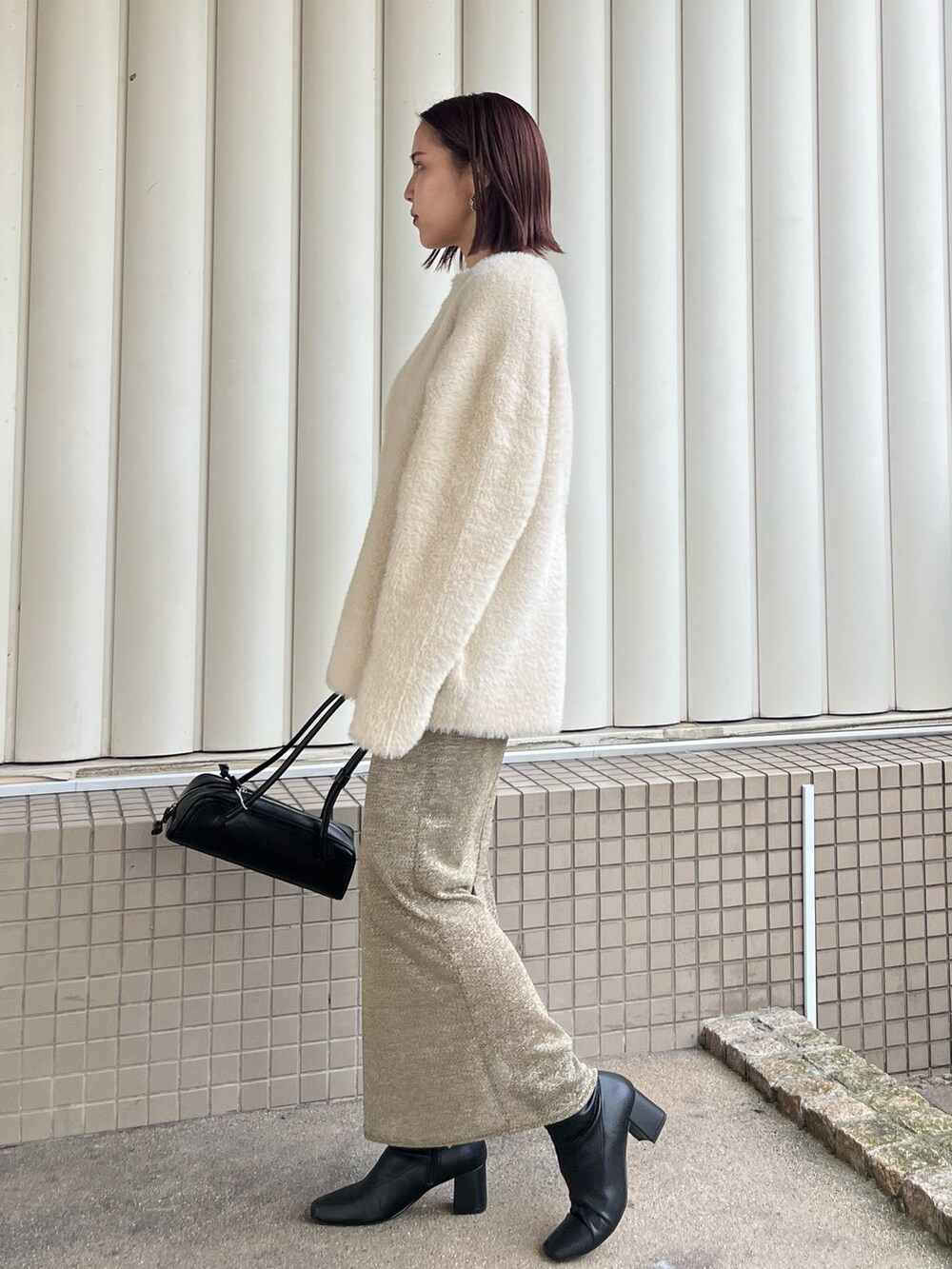 ホワイト系のカーディガン/ボレロ、ゴールド系のスカート、ブラック系のニット/セーターを着用したレディースの冬コーディネートの2枚目の写真