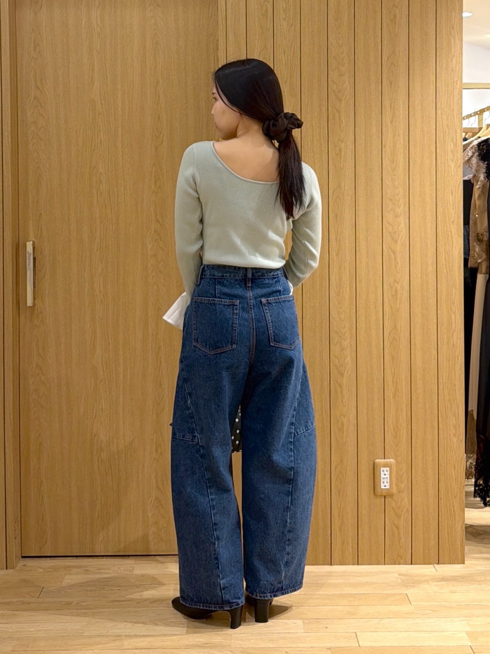 ブルー系のデニムパンツ、ブラック系のブーツ、ブラック系のハンドバッグを着用したレディースの秋コーディネートの3枚目の写真