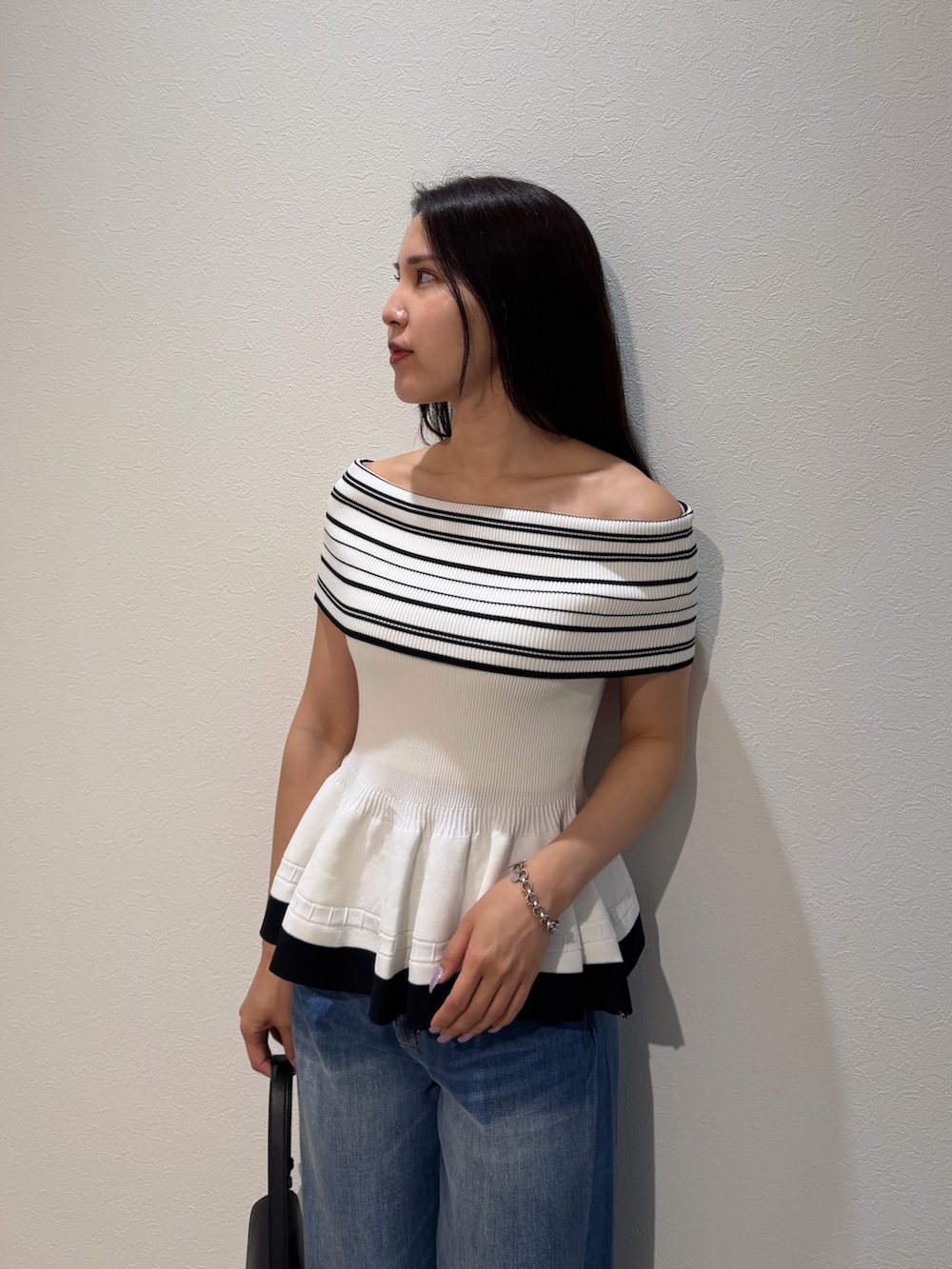 ブルー系のデニムパンツ、ブラック系のハンドバッグ、グリーン系のパンプスを着用したレディースの夏コーディネートの4枚目の写真