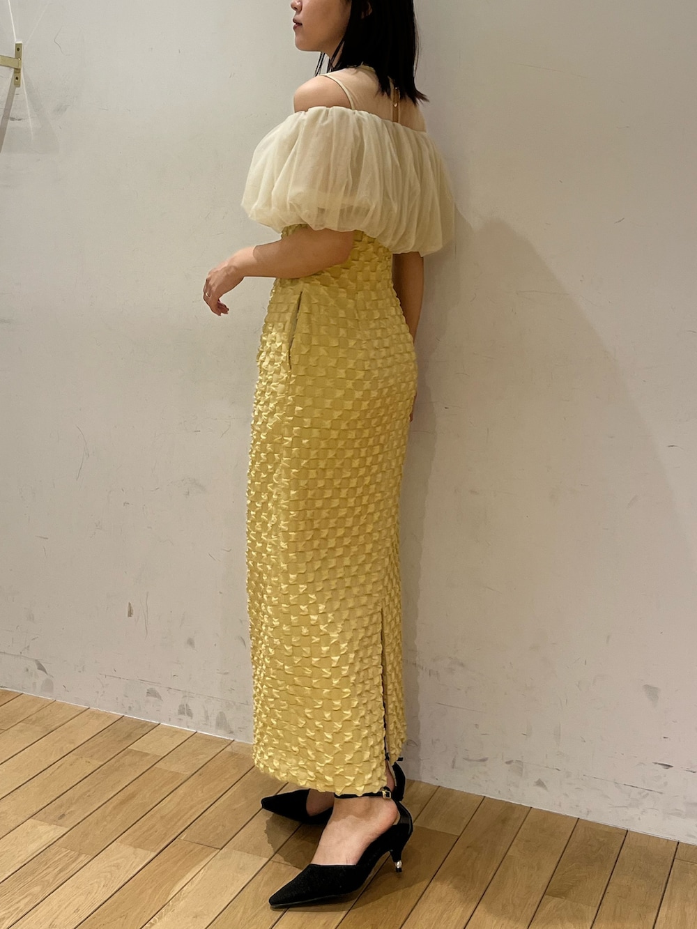 イエロー系のドレス、ブラック系のパンプスを着用したレディースの春コーディネートの2枚目の写真