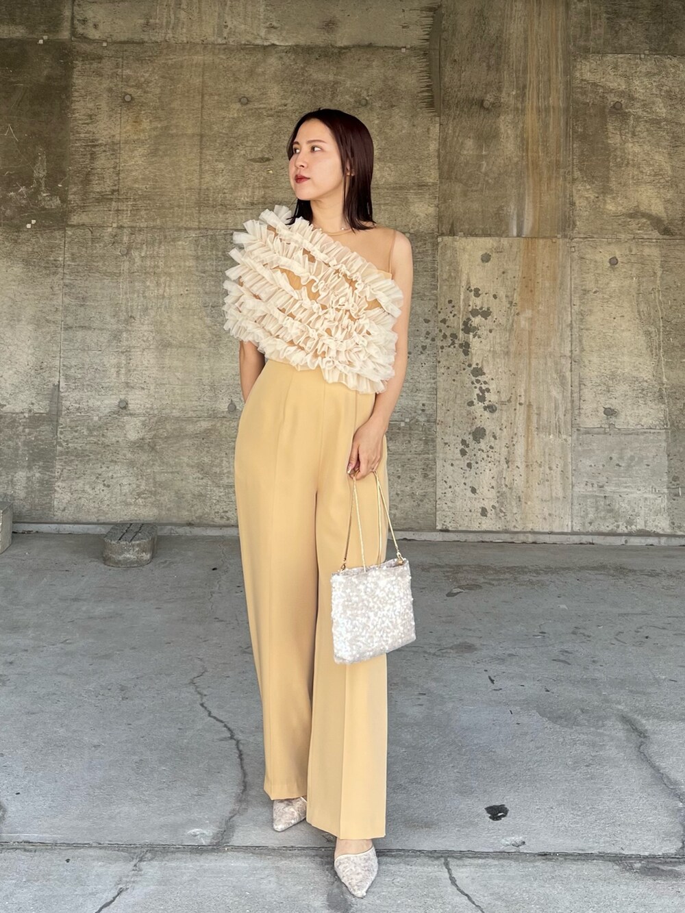 イエロー系のパンツドレス、ベージュ系のショルダーバッグ、ベージュ系のパンプスを着用したレディースの春コーディネートの4枚目の写真