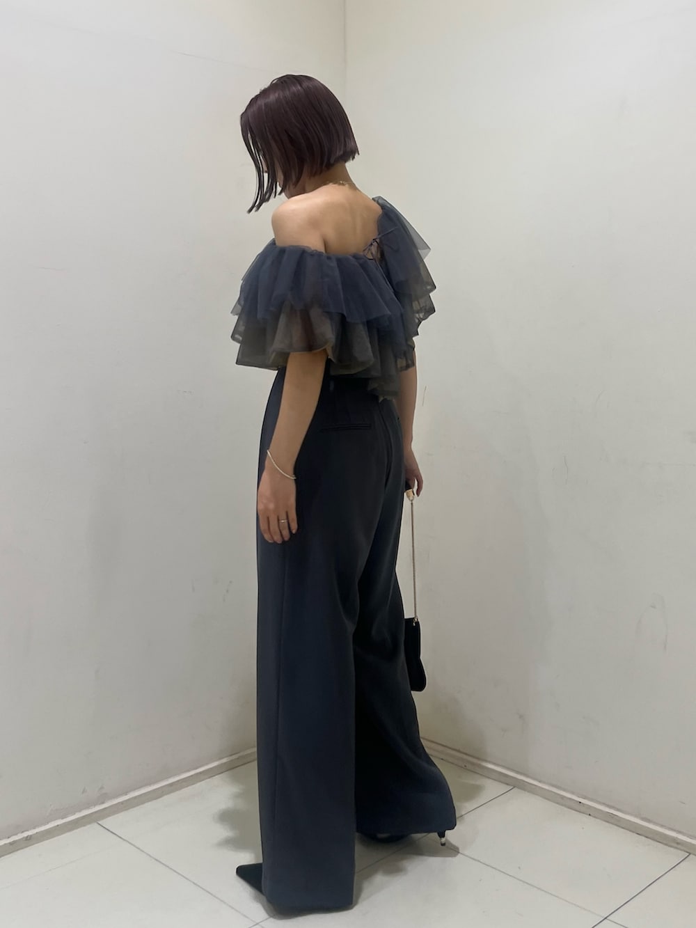 ブラック系のパンプス、ブラック系のクラッチバッグ、グレー系のパンツドレスを着用したレディースの夏コーディネートの3枚目の写真