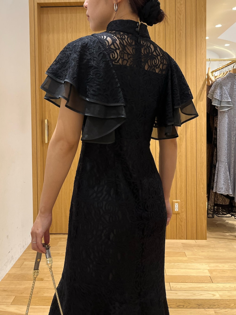 ブラック系のドレス、シルバー系のパンプス、シルバー系のクラッチバッグを着用したレディースの秋コーディネートの6枚目の写真