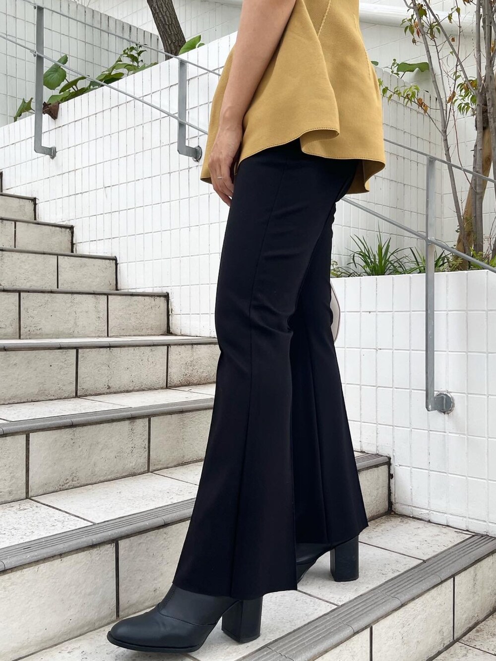 イエロー系のニット/セーター、ホワイト系のハンドバッグ、ブラック系のその他パンツを着用したレディースの秋コーディネートの4枚目の写真