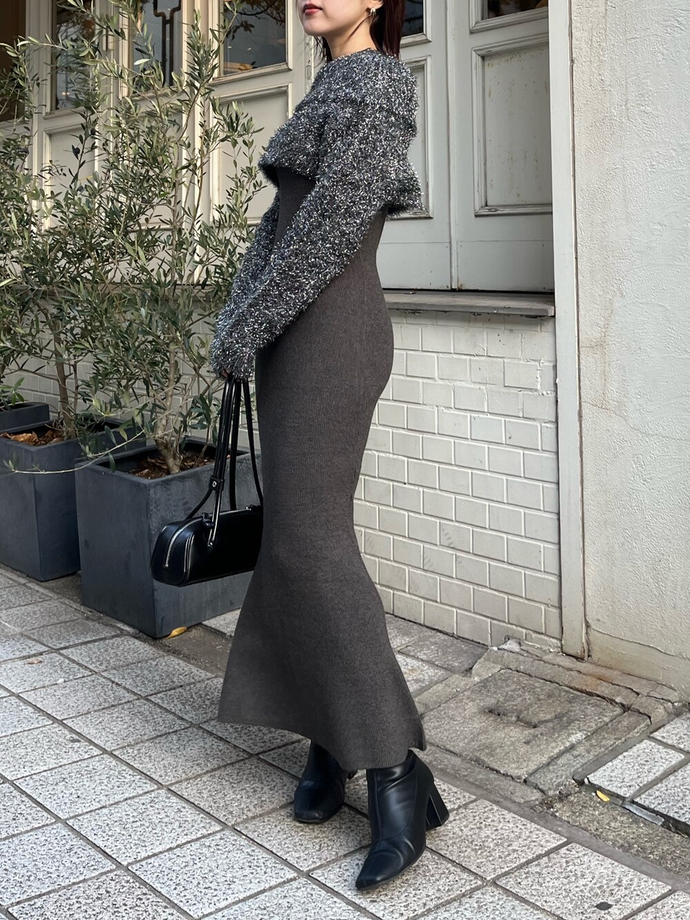 グレー系のワンピース、ブラック系のブーツを着用したレディースの冬コーディネートの2枚目の写真