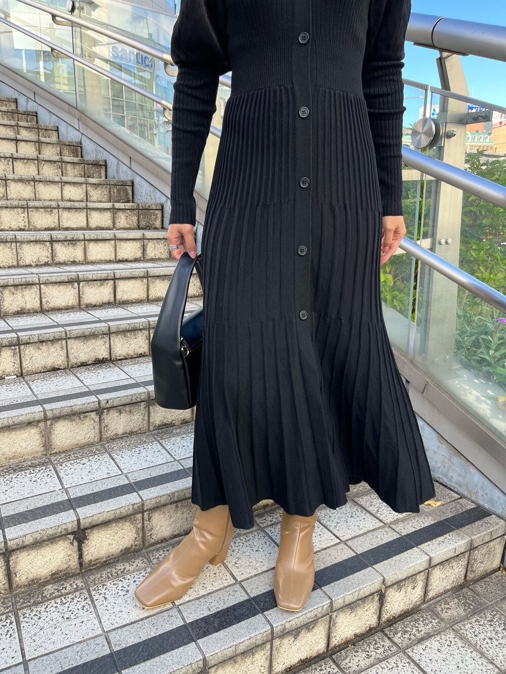 ブラック系のワンピース、ベージュ系のブーツ、ブラック系のハンドバッグを着用したレディースの秋コーディネートの6枚目の写真