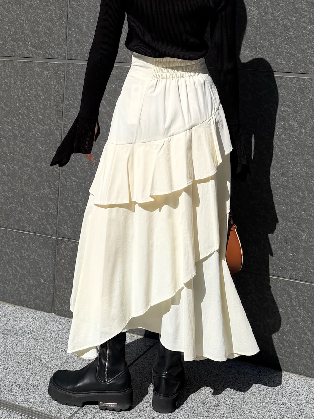 ホワイト系のスカート、ブラック系のニット/セーター、ブラウン系のハンドバッグを着用したレディースの冬コーディネートの6枚目の写真