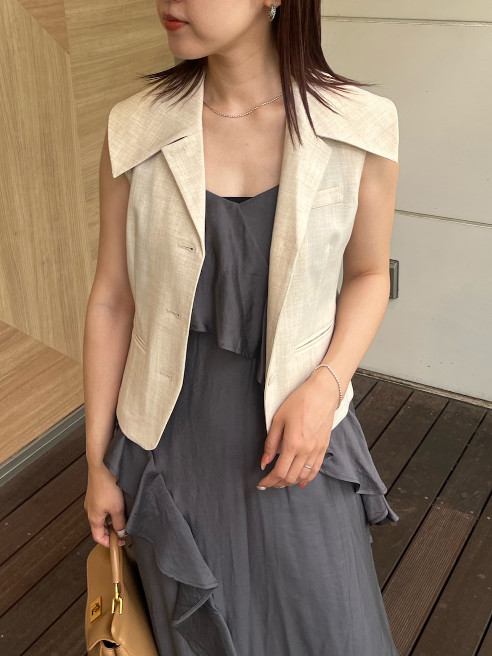 ホワイト系のベスト、グレー系のワンピース、ブラウン系のハンドバッグを着用したレディースの夏コーディネートの4枚目の写真