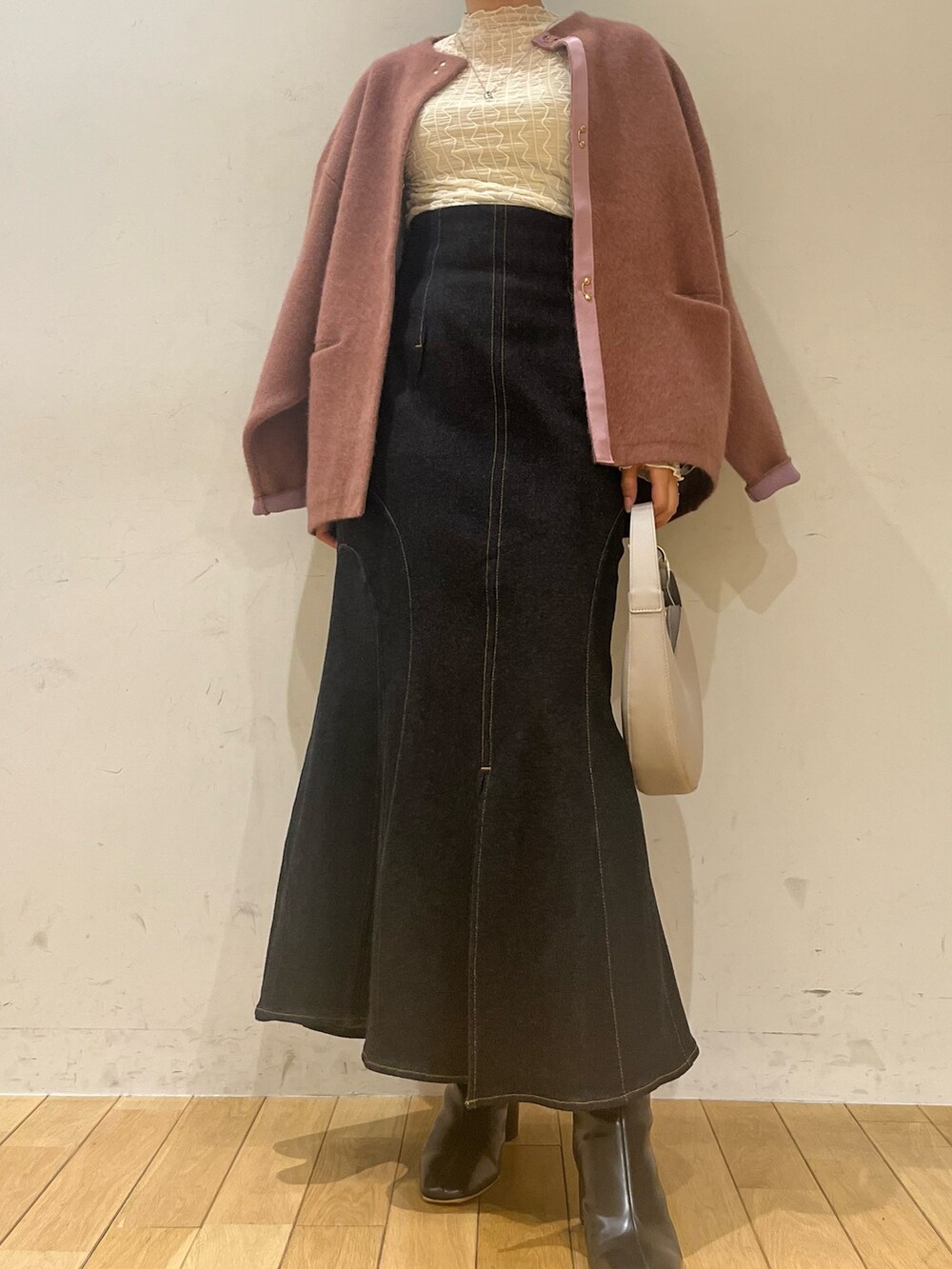 ブラック系のハンドバッグ、ブラック系のデニムスカート、ブラック系のブーツを着用したレディースの秋コーディネートの6枚目の写真