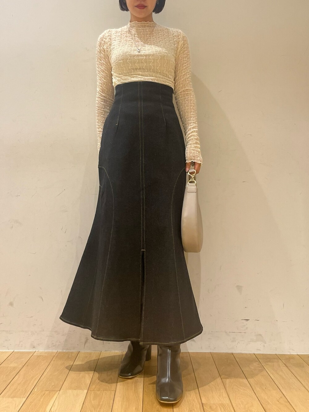 ブラック系のハンドバッグ、ブラック系のデニムスカート、ブラック系のブーツを着用したレディースの秋コーディネートの7枚目の写真