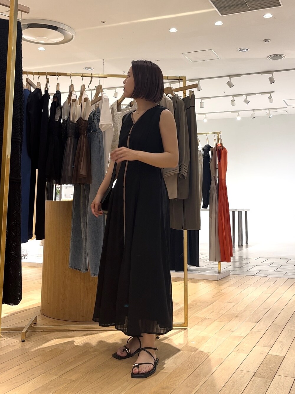 ブラック系のワンピース、ブラック系のサンダル、ホワイト系のシャツ/ブラウスを着用したレディースの夏コーディネートの2枚目の写真