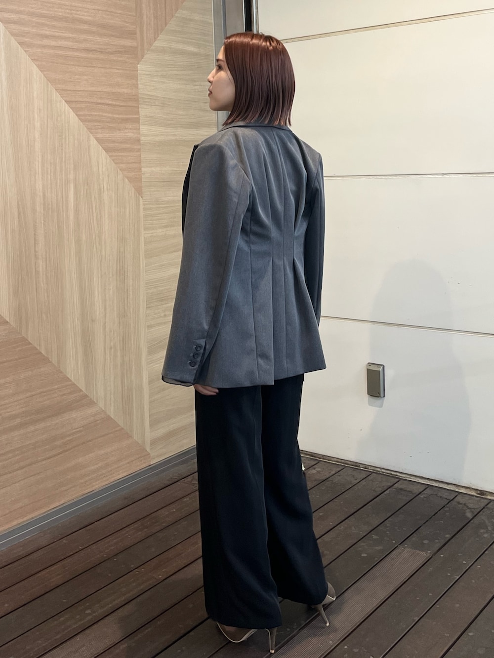 ゴールド系のハンドバッグ、その他のパンツドレス、グレー系のテーラードジャケットを着用したレディースの秋コーディネートの3枚目の写真