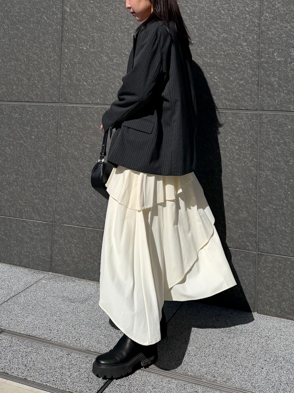 ホワイト系のスカート、ブラック系のニット/セーター、ブラック系のハンドバッグを着用したレディースの冬コーディネートの2枚目の写真