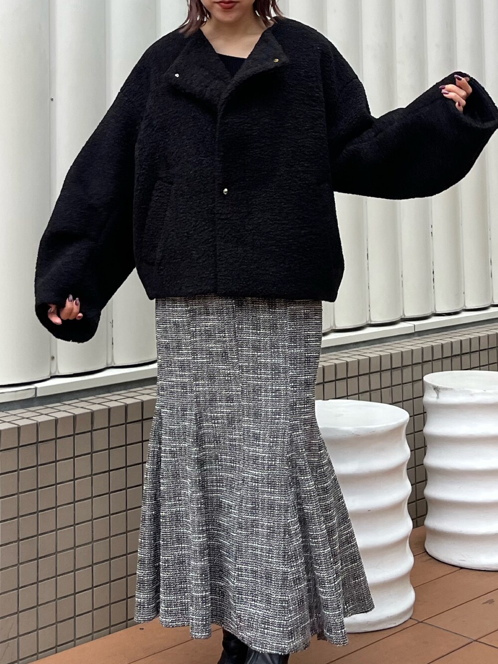 ブラック系のブルゾン、ブラック系のニット/セーター、ブラック系のスカートを着用したレディースの秋コーディネートの4枚目の写真