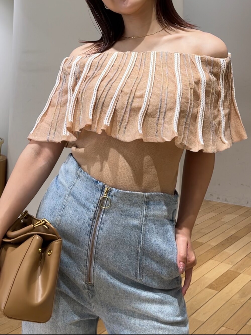 ブルー系のデニムパンツ、ホワイト系のサンダル、ブラウン系のハンドバッグを着用したレディースの春コーディネートの5枚目の写真