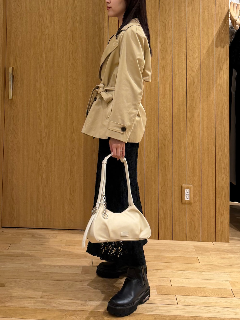 ブラック系のワンピース、ベージュ系のトレンチコートを着用したレディースの春コーディネートの2枚目の写真