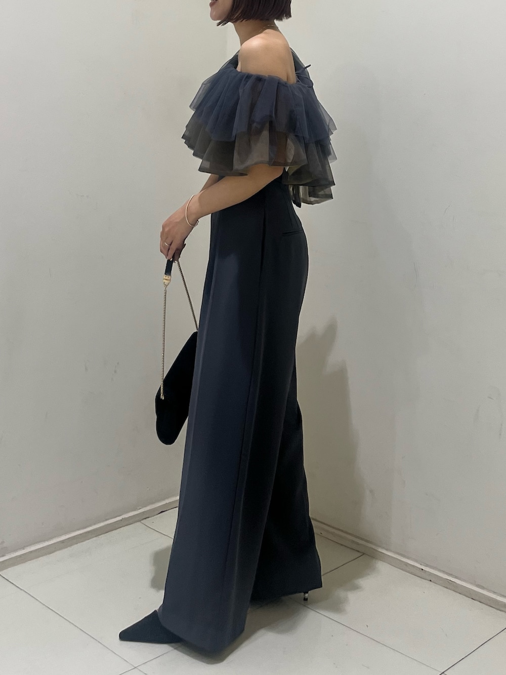 ブラック系のパンプス、ブラック系のクラッチバッグ、グレー系のパンツドレスを着用したレディースの夏コーディネートの2枚目の写真