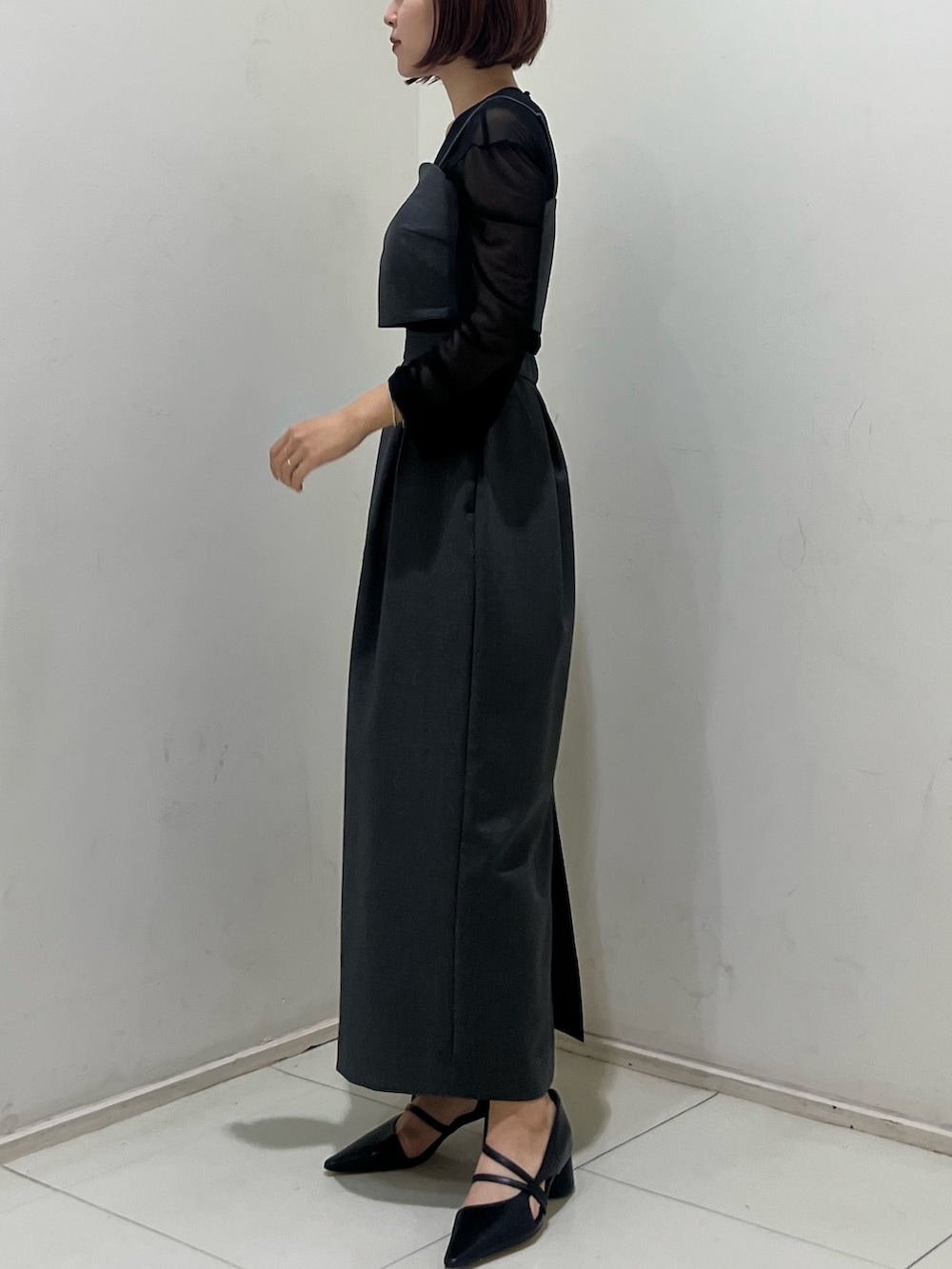 グレー系のドレス、ブラック系のパンプス、シルバー系のハンドバッグを着用したレディースの夏コーディネートの2枚目の写真